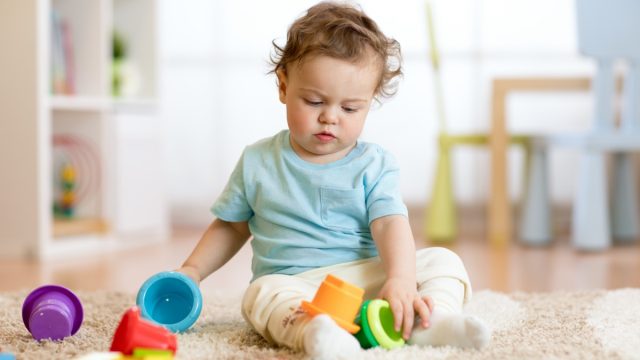 white toddler playing with stacking cups