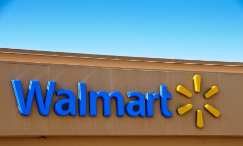 A blue Walmart sign and corporate logo on the front of a brown store.