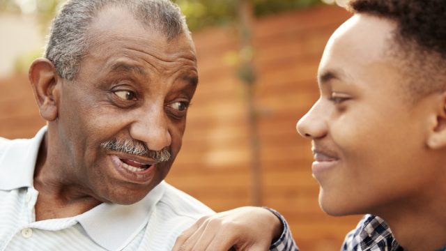 Senior black man talking with his young adult grandson, close up