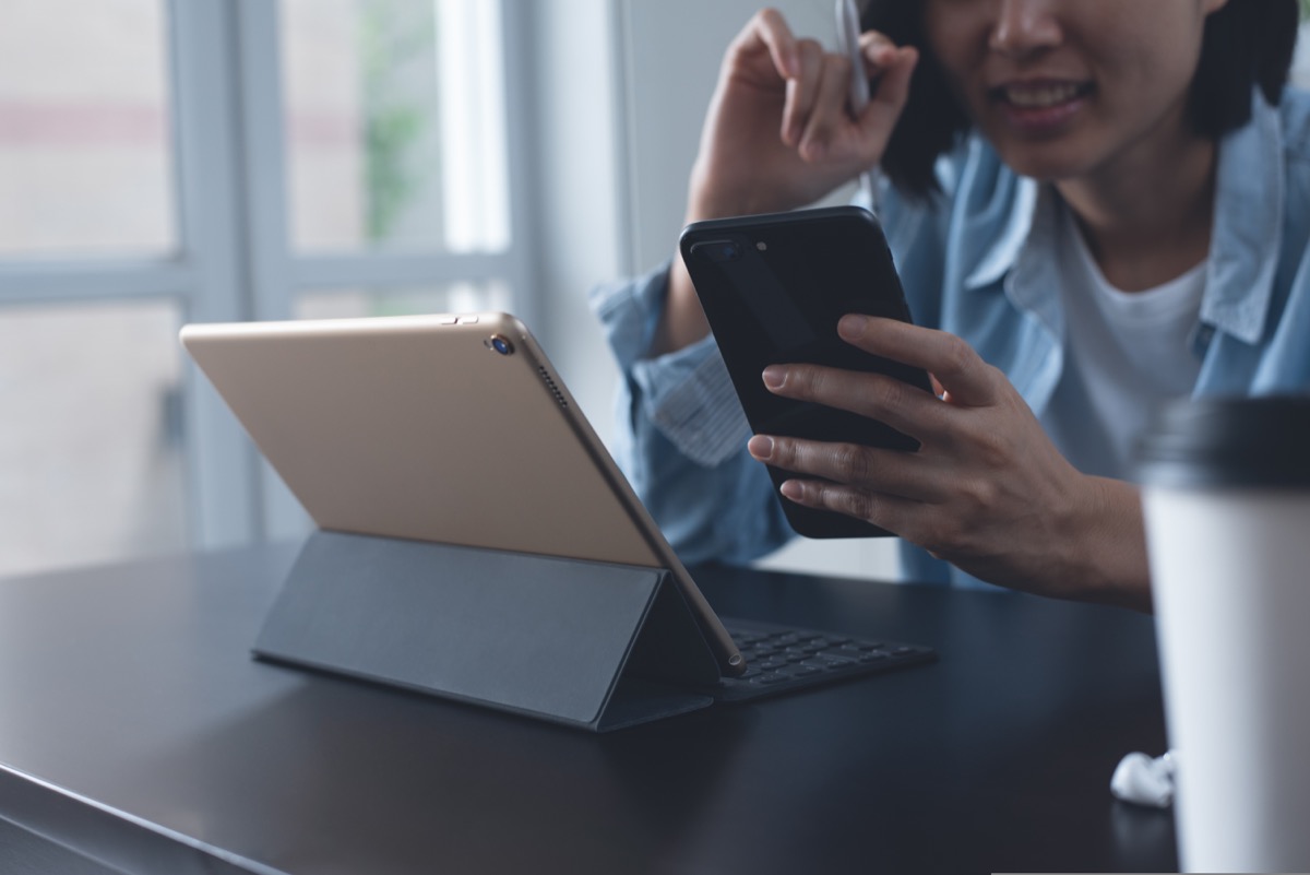 young asian woman on both ipad and phone