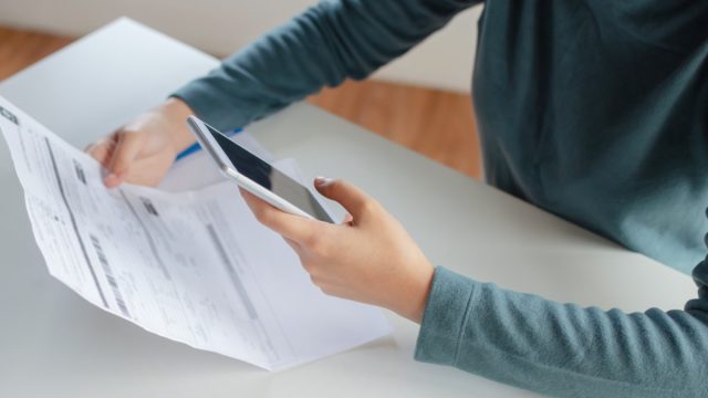 young white woman looking at cell phone bill