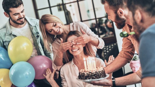 group of friends surprises a woman with a birthday cake
