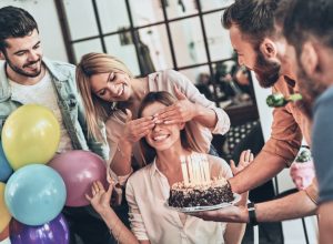 group of friends surprises a woman with a birthday cake