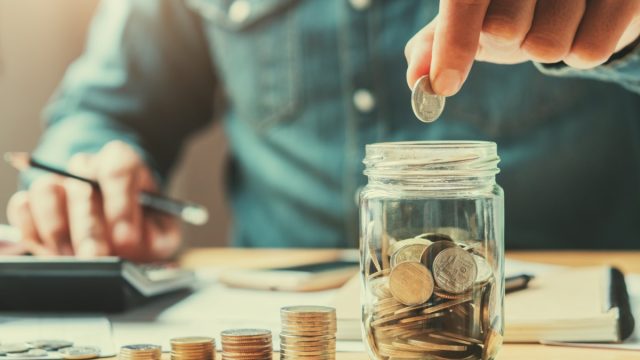 man putting coins in a jar