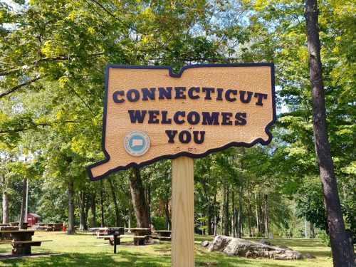 a wooden sign that says "Connecticut Welcomes You" in a park