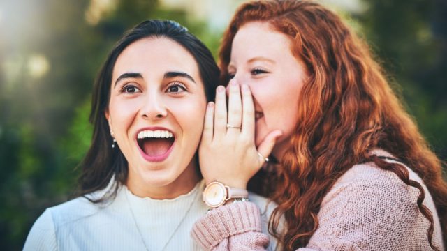 Shot of a woman whispering something into her friend's ear
