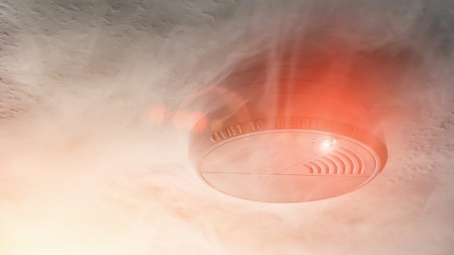 ceiling-mounted smoke alarm surrounded by smoke