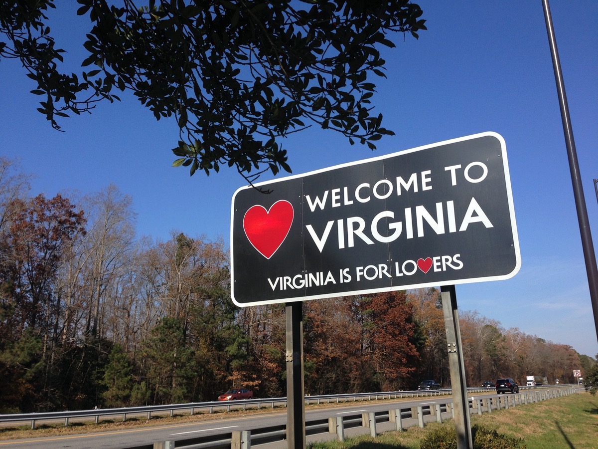 a black "Welcome to Virginia" sign off of a highway