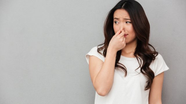 woman holding her nose from a bad smell