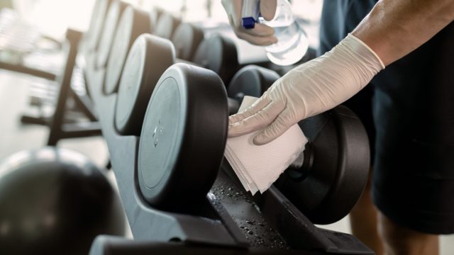 man in gloves disinfecting weights