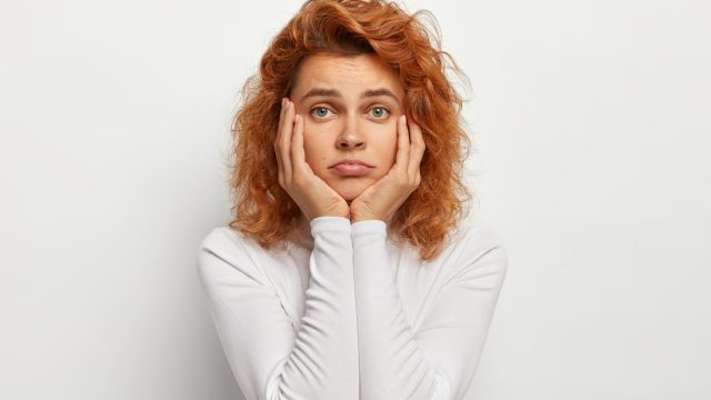 Lonely woman with hands on her face