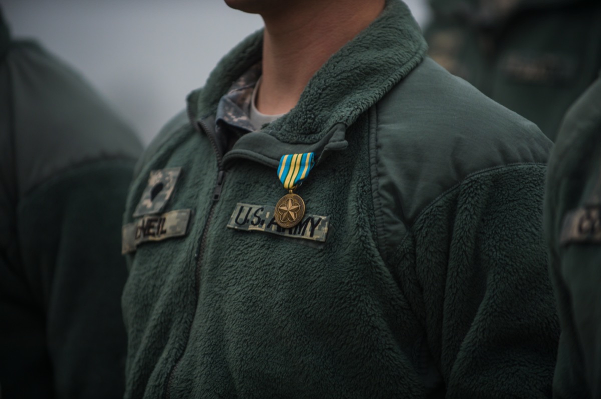 the chest of a military man wearing a green "U.S. Army" jacket with an award pinned to it