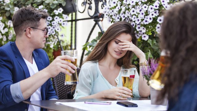 Woman cringing after man says something at bar
