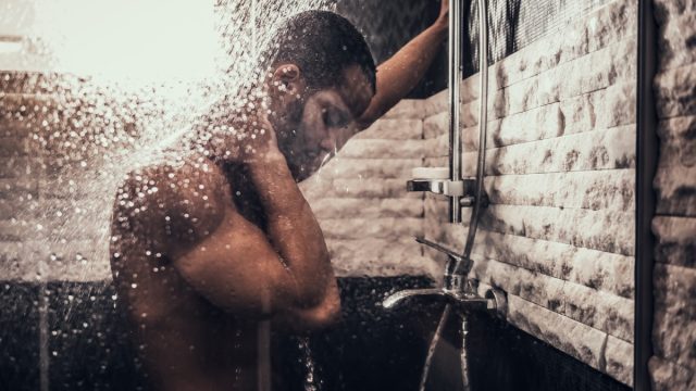 Man Taking Shower in Bathroom at Morning. Standing Man with Bare Torso in Bathroom. Personal Morning Routine. Fresh at Morning