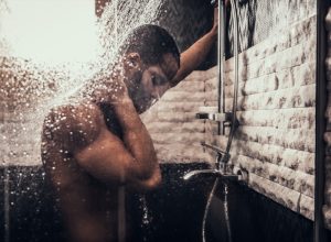 Man Taking Shower in Bathroom at Morning. Standing Man with Bare Torso in Bathroom. Personal Morning Routine. Fresh at Morning