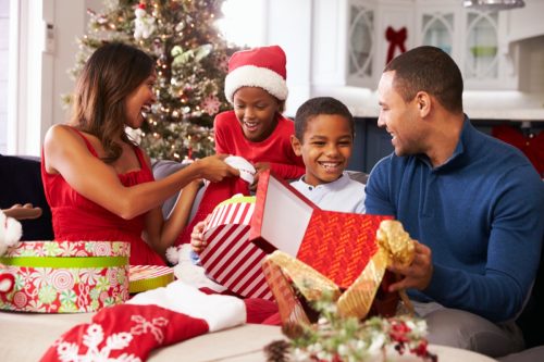 mother father and two young kids opening christmas presents