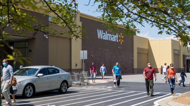 Kennesaw, GA / USA - 04/05/20: Walmart line outside the store with masked people practicing social distancing 6 feet apart during Covid-19 Corona Virus Pandemic.