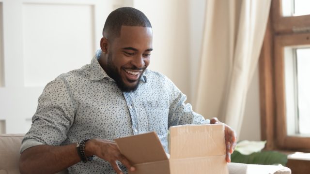 young man looking excited while opening cardboard box