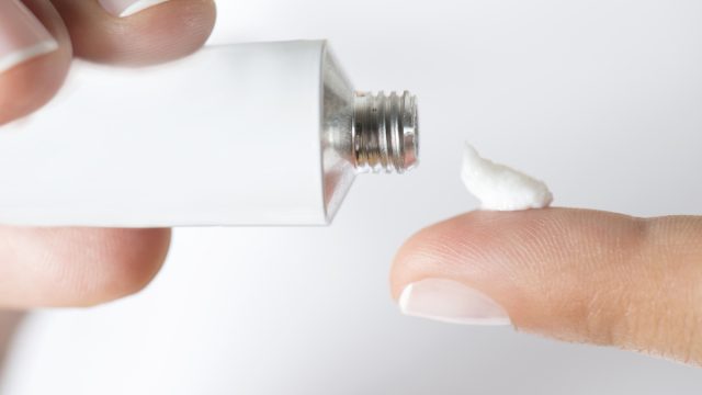 Woman is holding ointment tube in hand.