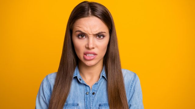 woman with a disgusted look on her face and wearing a jean jacket