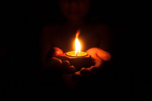 Hands holding a candle in darkness