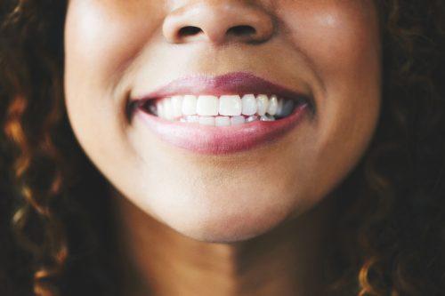 Closeup shot of a young woman smiling against a gray background