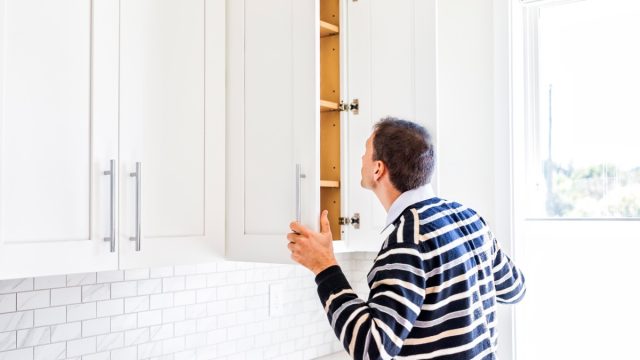 Man looking in kitchen cabinet