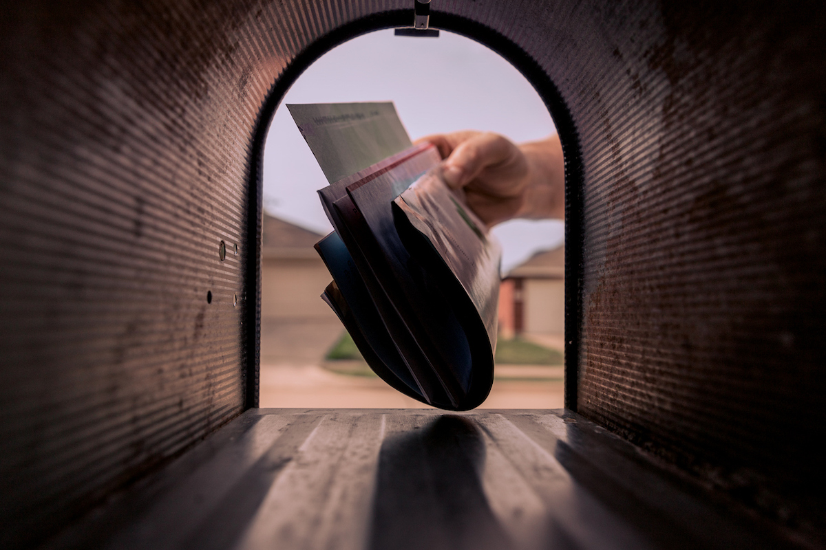 A hand removing mail from the mailbox.