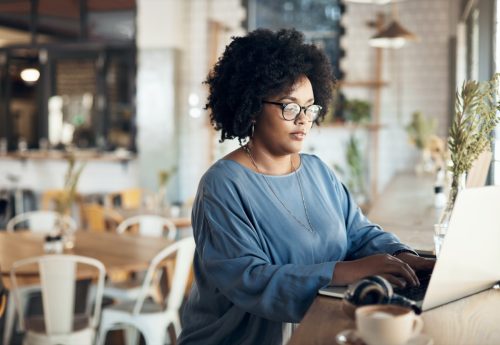 Cropped shot of an attractive young businesswoman sitting alone and working on her laptop in a cafe