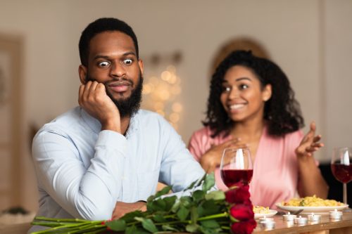 Young man being annoyed by young woman at dinner