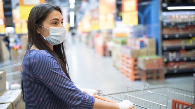Woman with face mask, shopping for groceries in a supermarket during COVID-19 pandemic