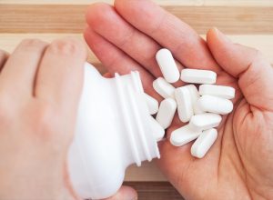 Woman taking magnesium pills out of a bottle. Close up.