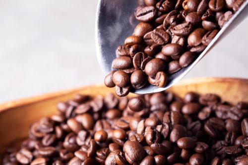 metal scoop pouring coffee beans