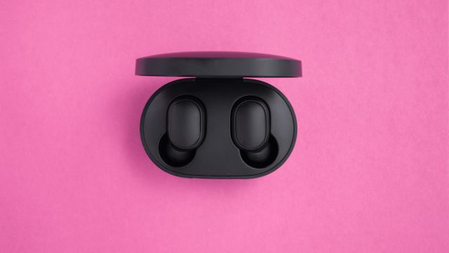 Wireless headphones in a mockup case on a bright pink background