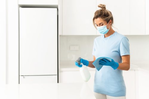 woman wearing gloves, mask, cleaning kitchen