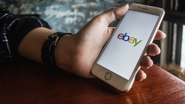 Hand holding iPhone with eBay app on the screen