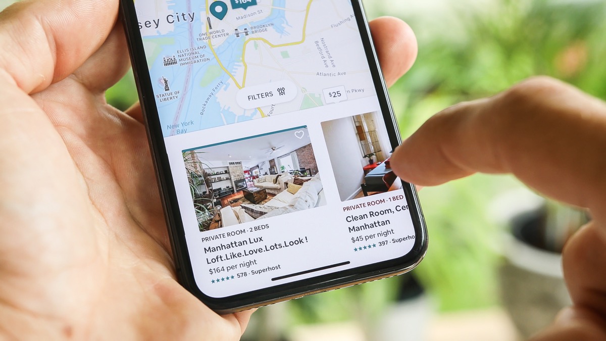 NEW YORK CITY, NY â€“ December 1, 2019: Female hand holding smartphone with Airbnb application. Woman trying to book home apartment room in New York City using Airbnb app