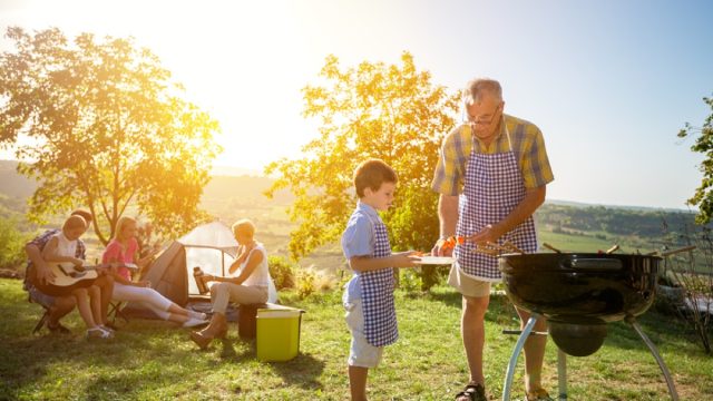 family barbecuing outside with tent in the background