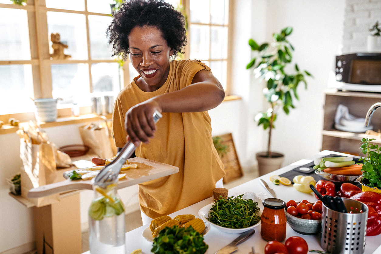 A woman cooking in the kitchen surrounded by vegetables