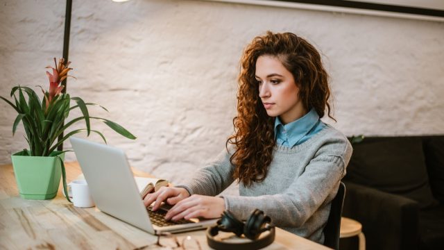 young woman reading report on laptop.