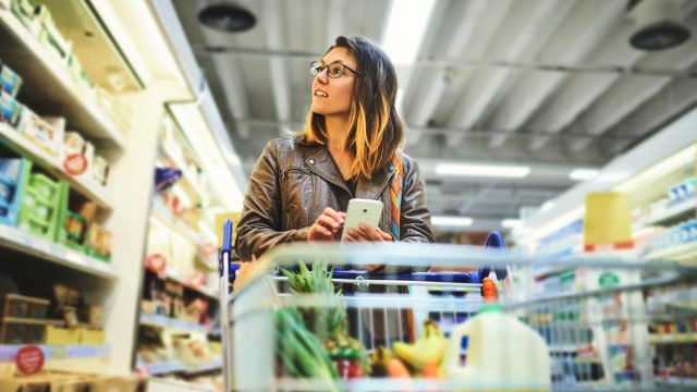 Shot of a young woman using a mobile phone in a grocery store