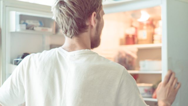 young man searching for food in fridge at home