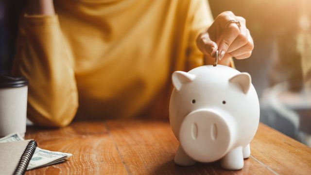 Woman putting money in piggy bank for retirement