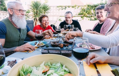 Happy senior friends having fun eating on patio at BBQ