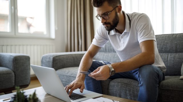Young man shopping online with credit card at home