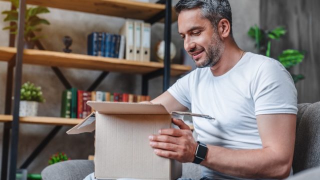 Happy middle aged man with cardboard boxes delivery at home