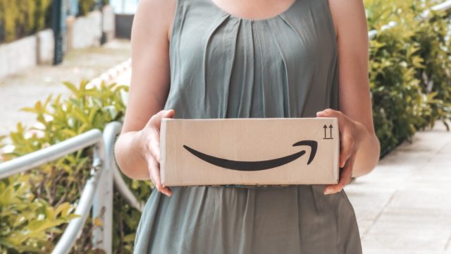 woman wearing gray dress and holding amazon box