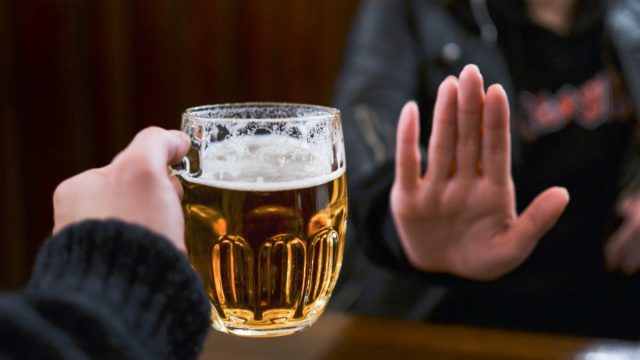 person holding out hand to indicate they don't want a glass of beer