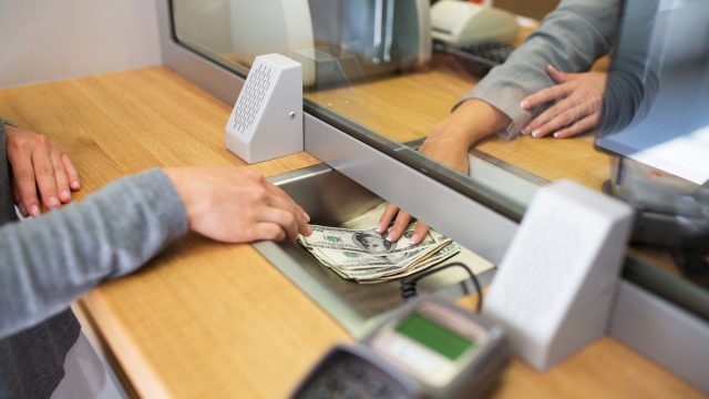 Person withdrawing money from bank teller