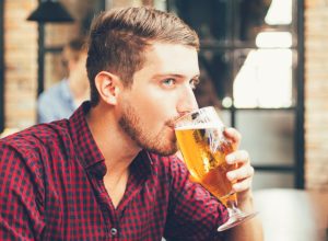 man drinking beer out of a glass